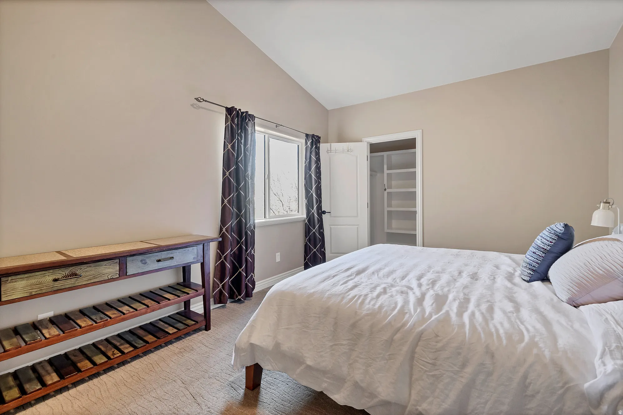 Bedroom with vaulted ceiling, a spacious closet, and light colored carpet