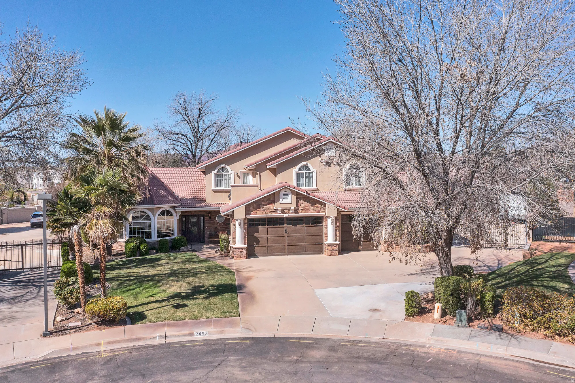 View of front facade with a tiled roof, stone siding, concrete driveway, and stucco siding