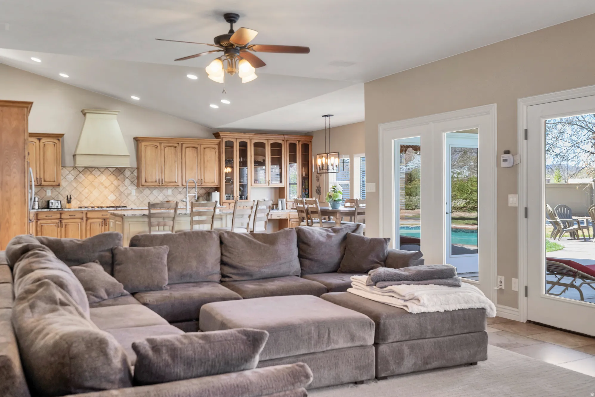 Living room featuring a ceiling fan, vaulted ceiling, and a chandelier