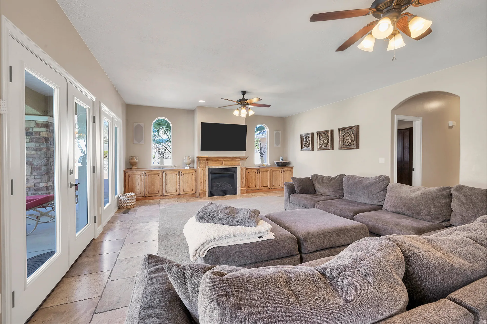 Living room with a ceiling fan, arched walkways, and a glass covered fireplace