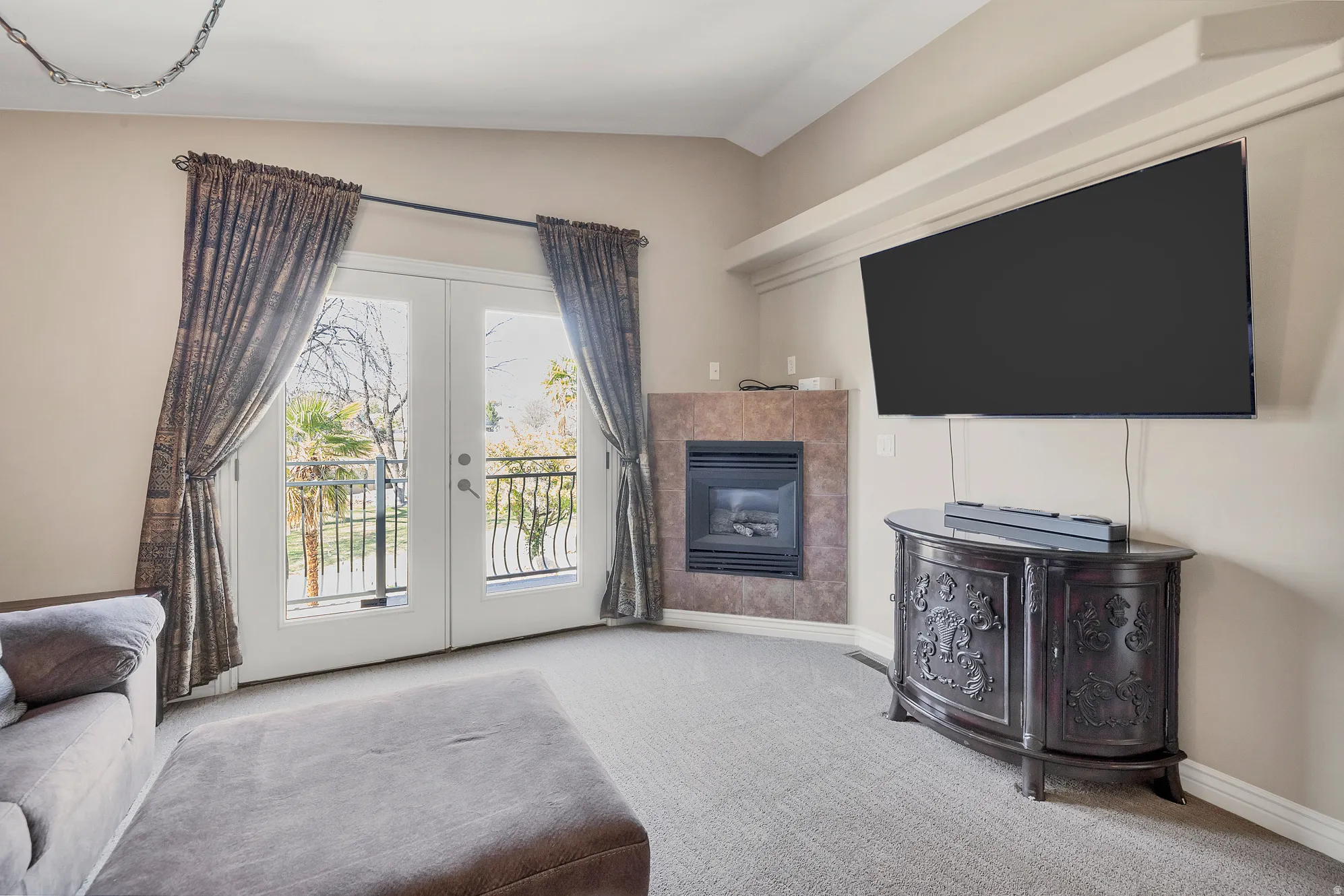 Carpeted living area featuring french doors, vaulted ceiling, and a tiled fireplace