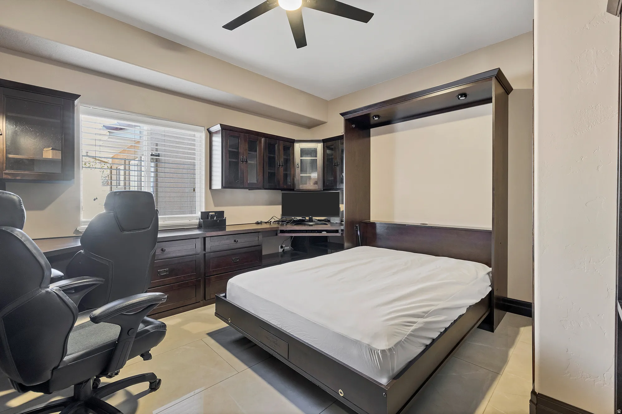 Bedroom featuring an office area, light tile patterned flooring, and a ceiling fan