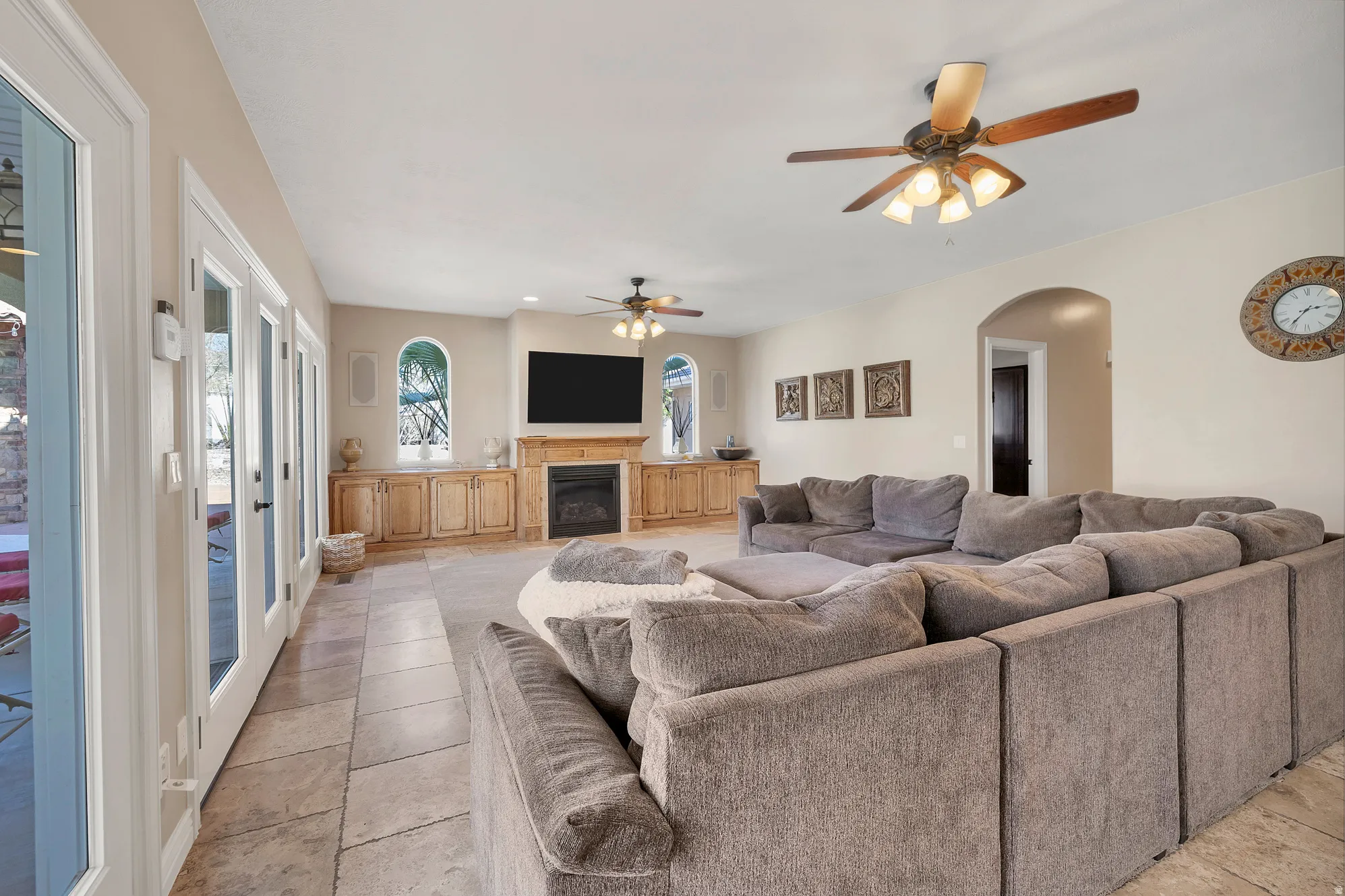 Living area featuring ceiling fan, arched walkways, and a glass covered fireplace