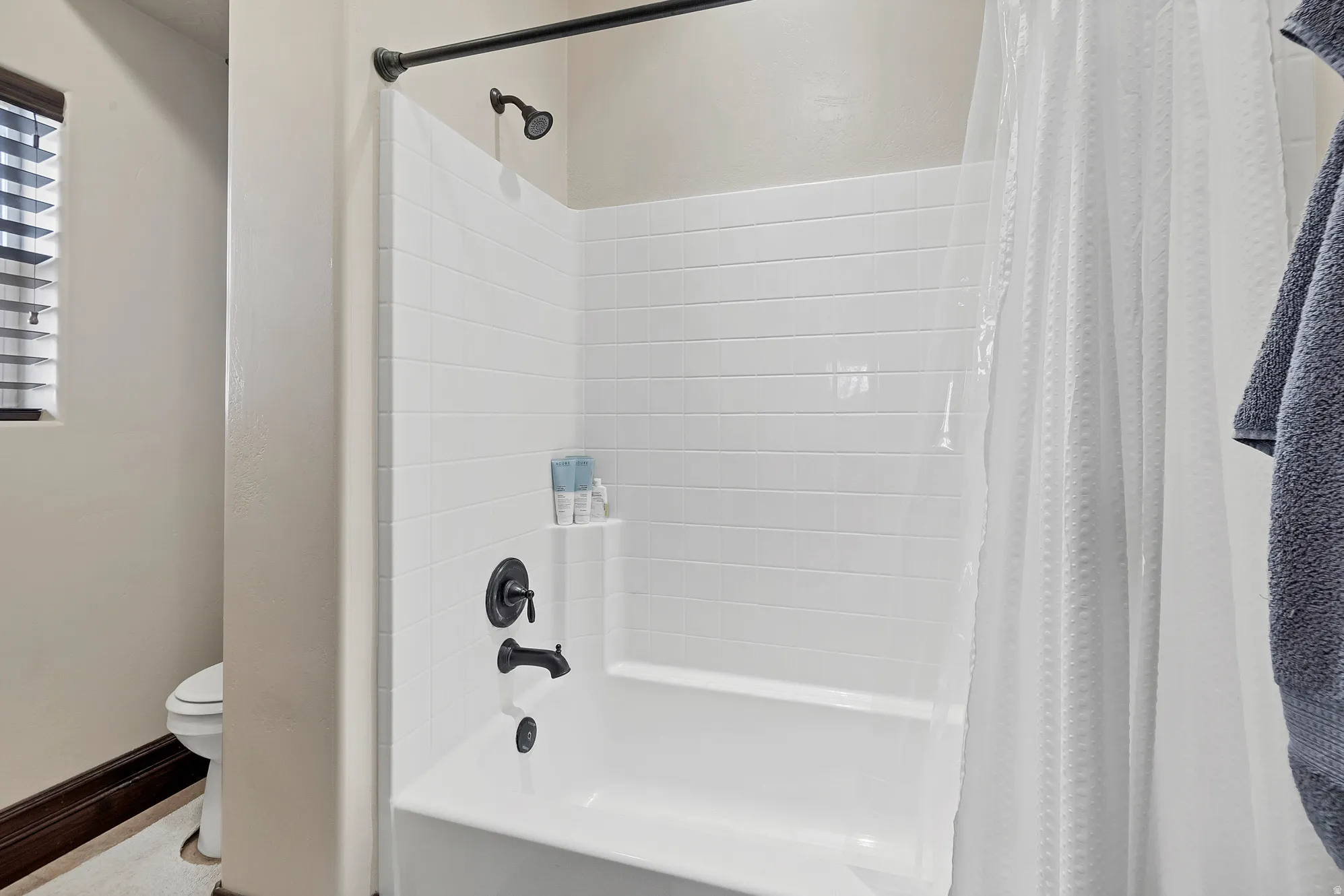 Bathroom featuring toilet and shower / bath combination with curtain