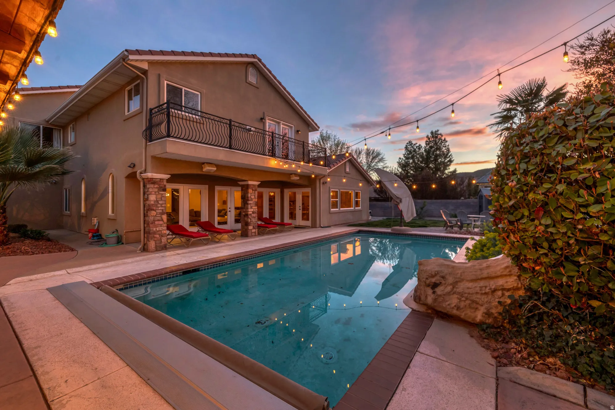 Back of house featuring a patio, an outdoor pool, stucco siding, and stone siding