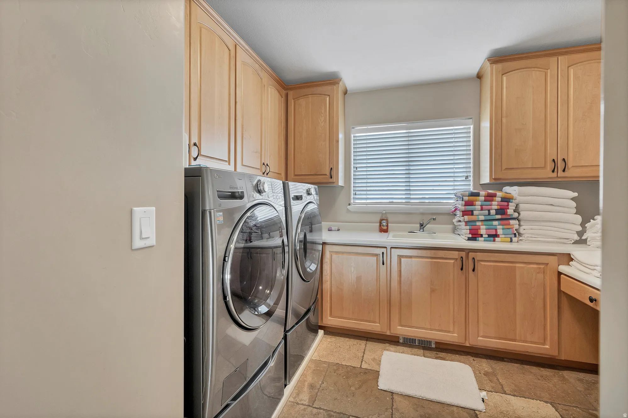 Laundry area with stone tile floors, independent washer and dryer, and cabinet space
