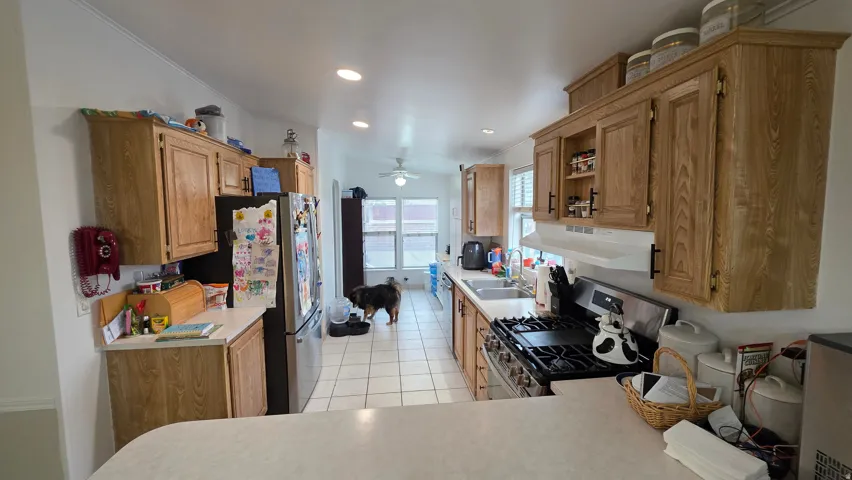 Kitchen featuring stainless steel appliances, light countertops, extractor fan, recessed lighting, and light tile patterned floors