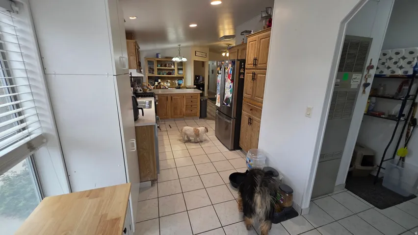 Kitchen with freestanding refrigerator, light tile patterned floors, a heating unit, pendant lighting, and light countertops