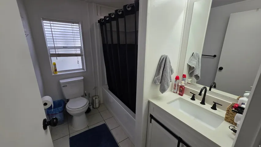 Full bath with vanity, shower / bathtub combination with curtain, and light tile patterned floors