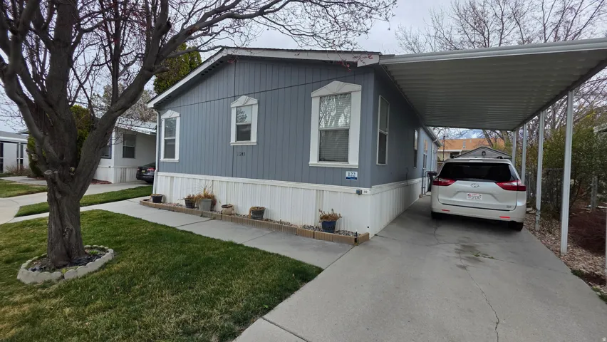 Manufactured / mobile home with an attached carport, driveway, and a front yard