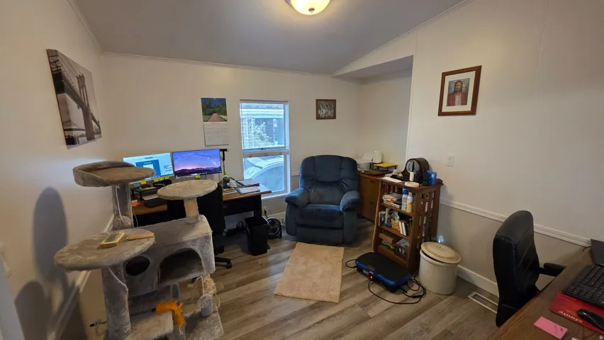 Office space featuring wood finished floors, ornamental molding, and lofted ceiling