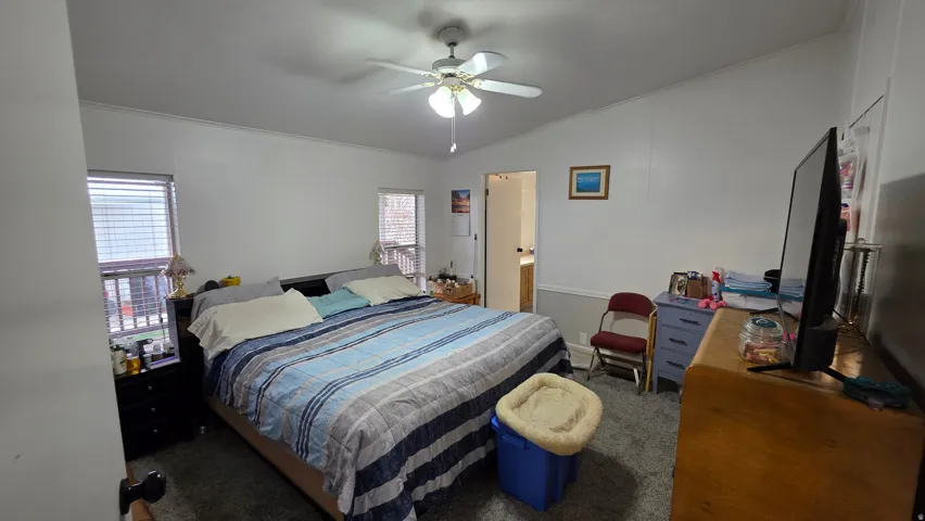 Bedroom with dark carpet, ornamental molding, vaulted ceiling, and a ceiling fan
