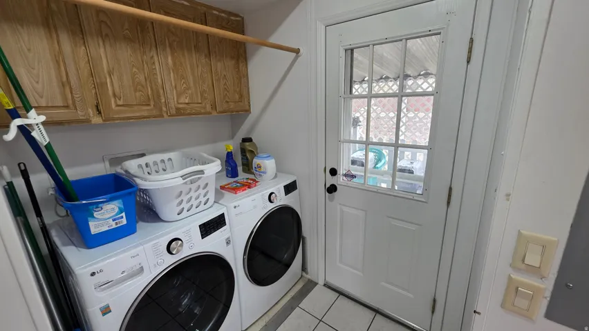 Laundry area featuring cabinet space, washing machine and dryer, and light tile patterned floors