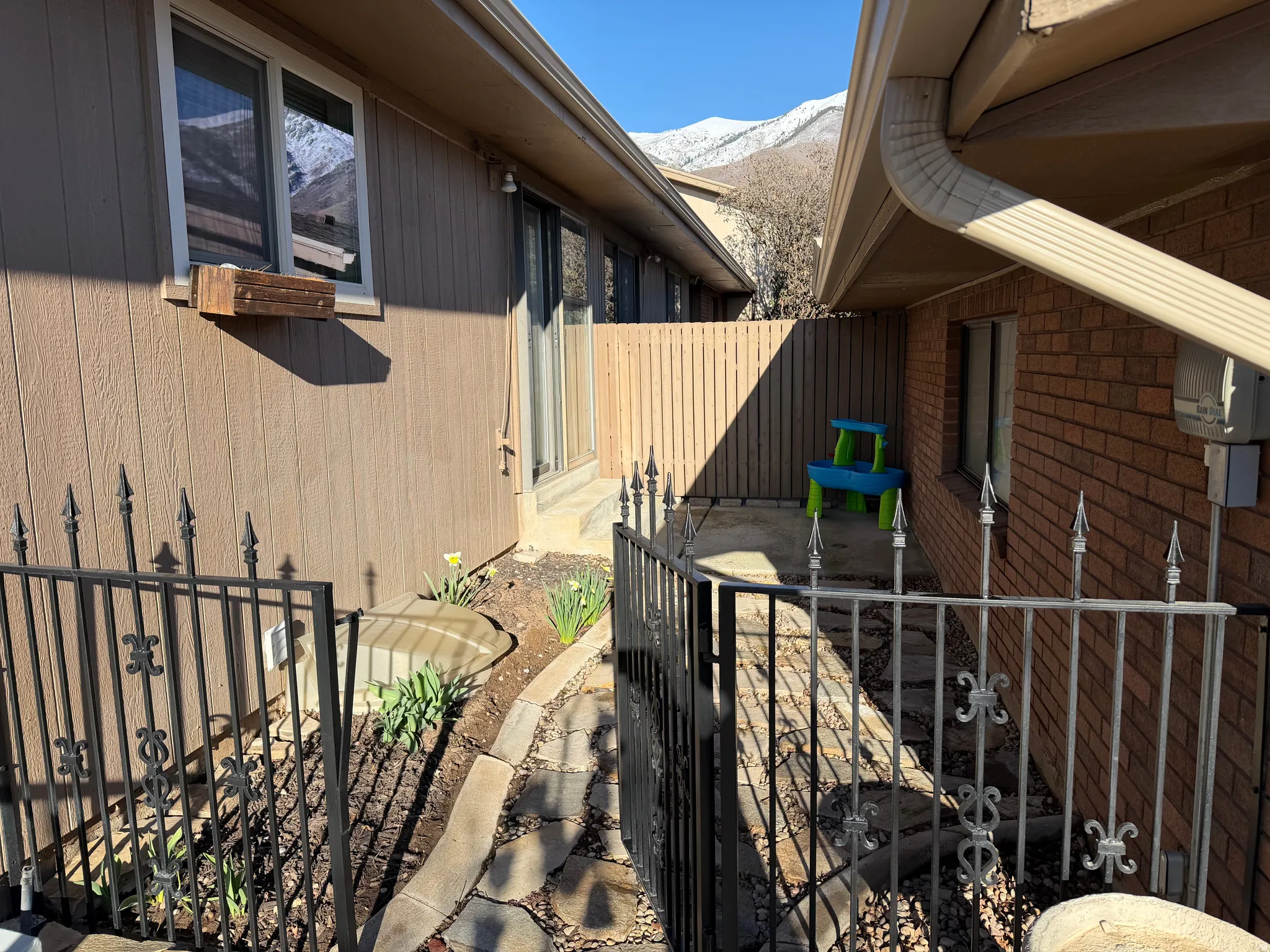 View of side of home featuring a patio, a mountain view, a gate, and brick siding
