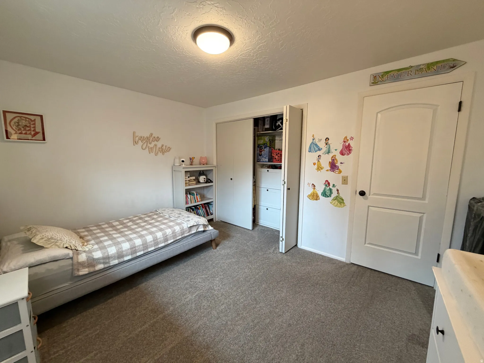 Bedroom featuring dark colored carpet, a textured ceiling, and a closet