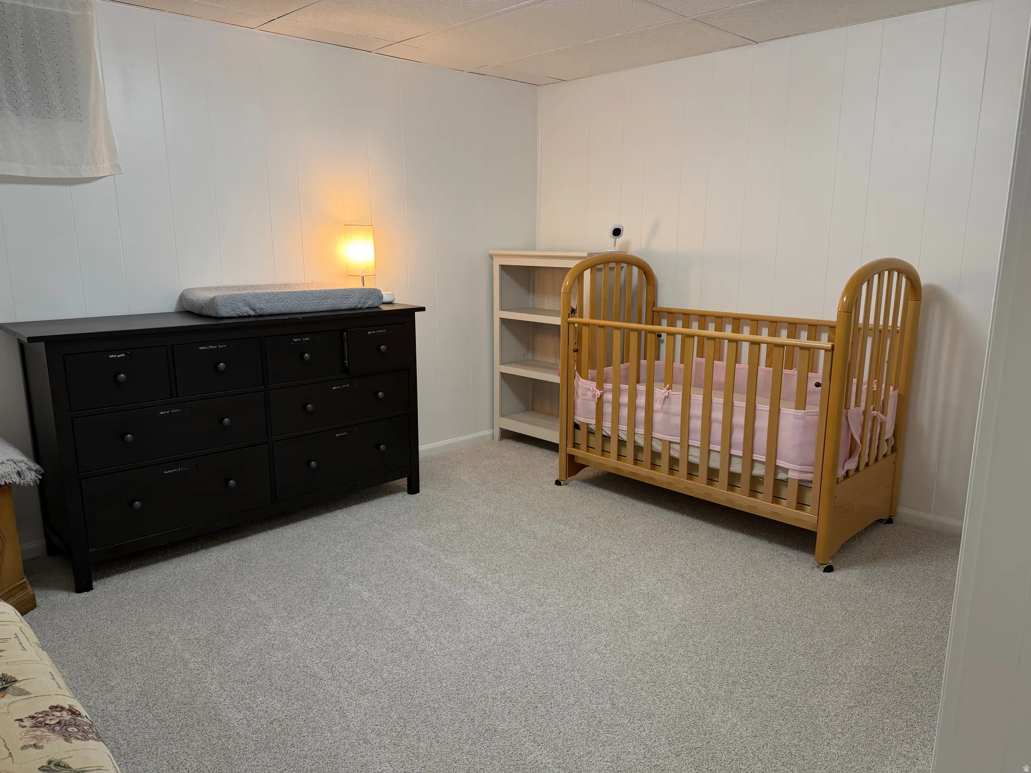 Bedroom with light colored carpet and a nursery area
