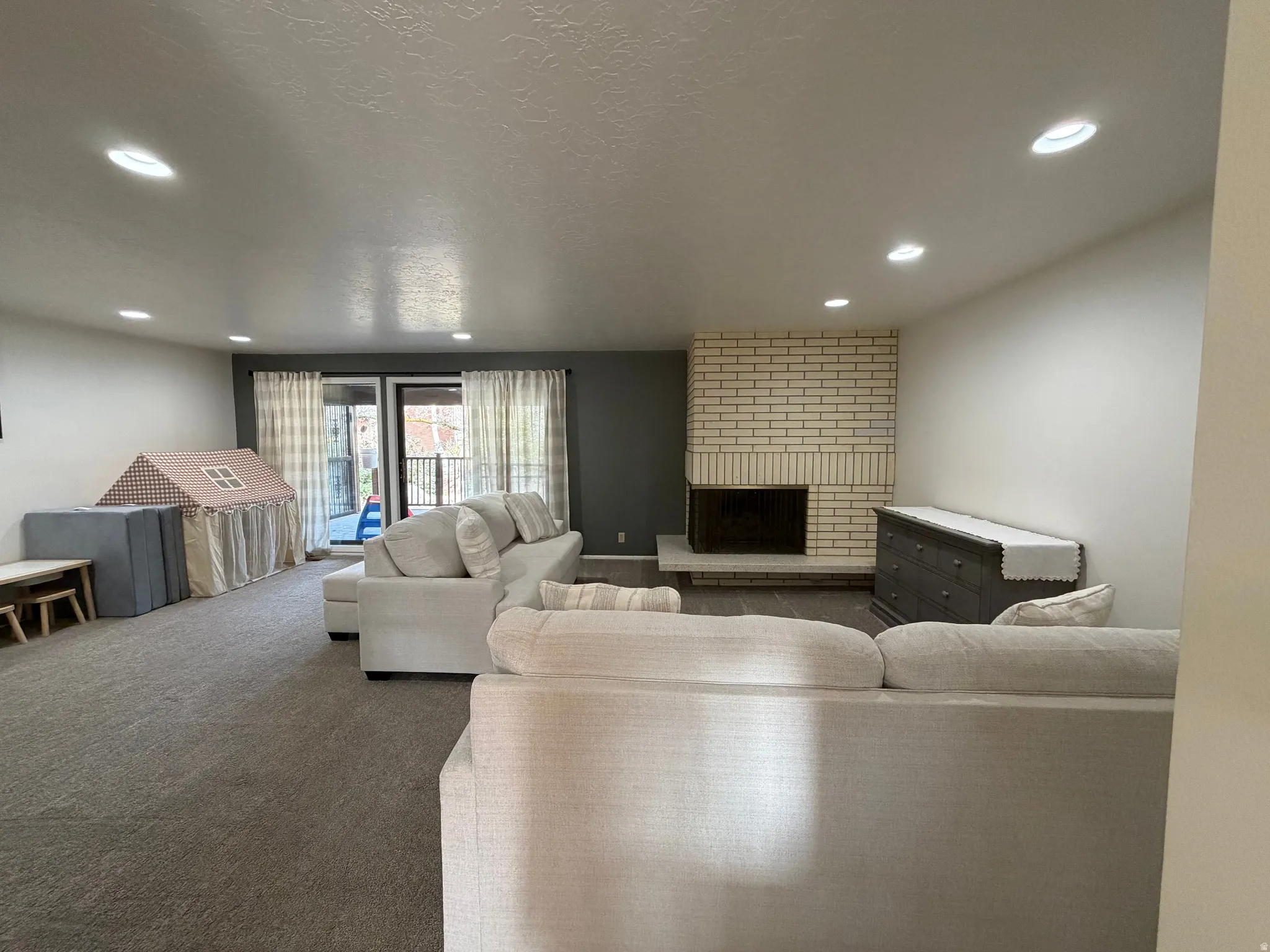 Carpeted living room with a textured ceiling, a fireplace, and recessed lighting