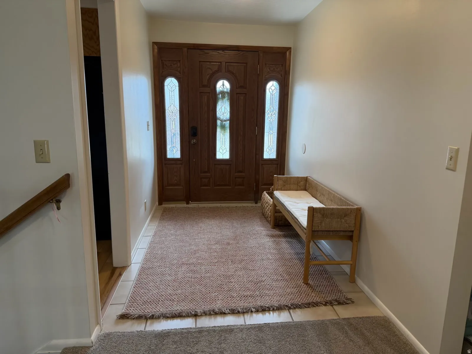 Foyer with light tile patterned flooring and light colored carpet