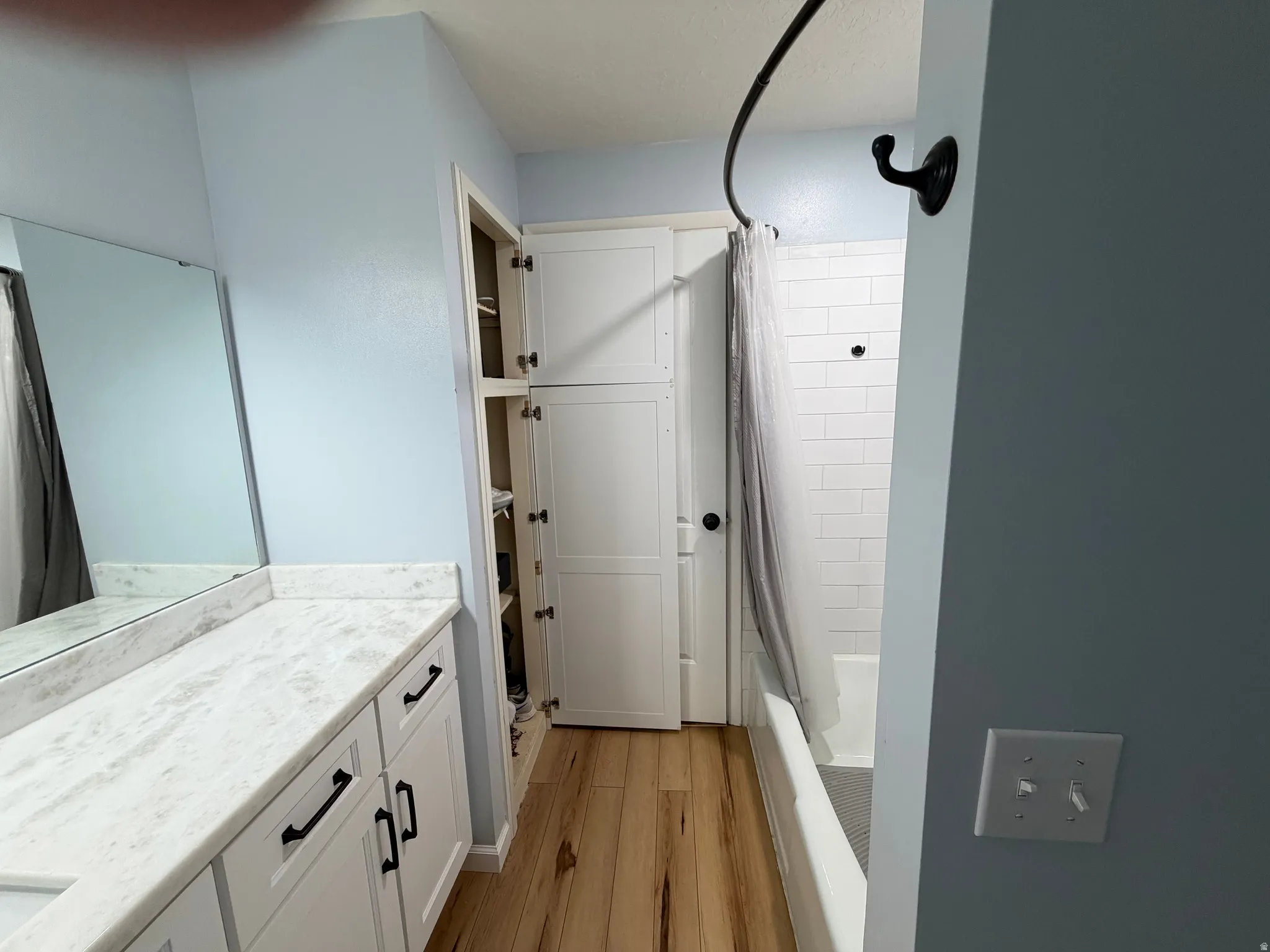 Full bath with vanity, shower / bath combo with shower curtain, and light wood-style floors