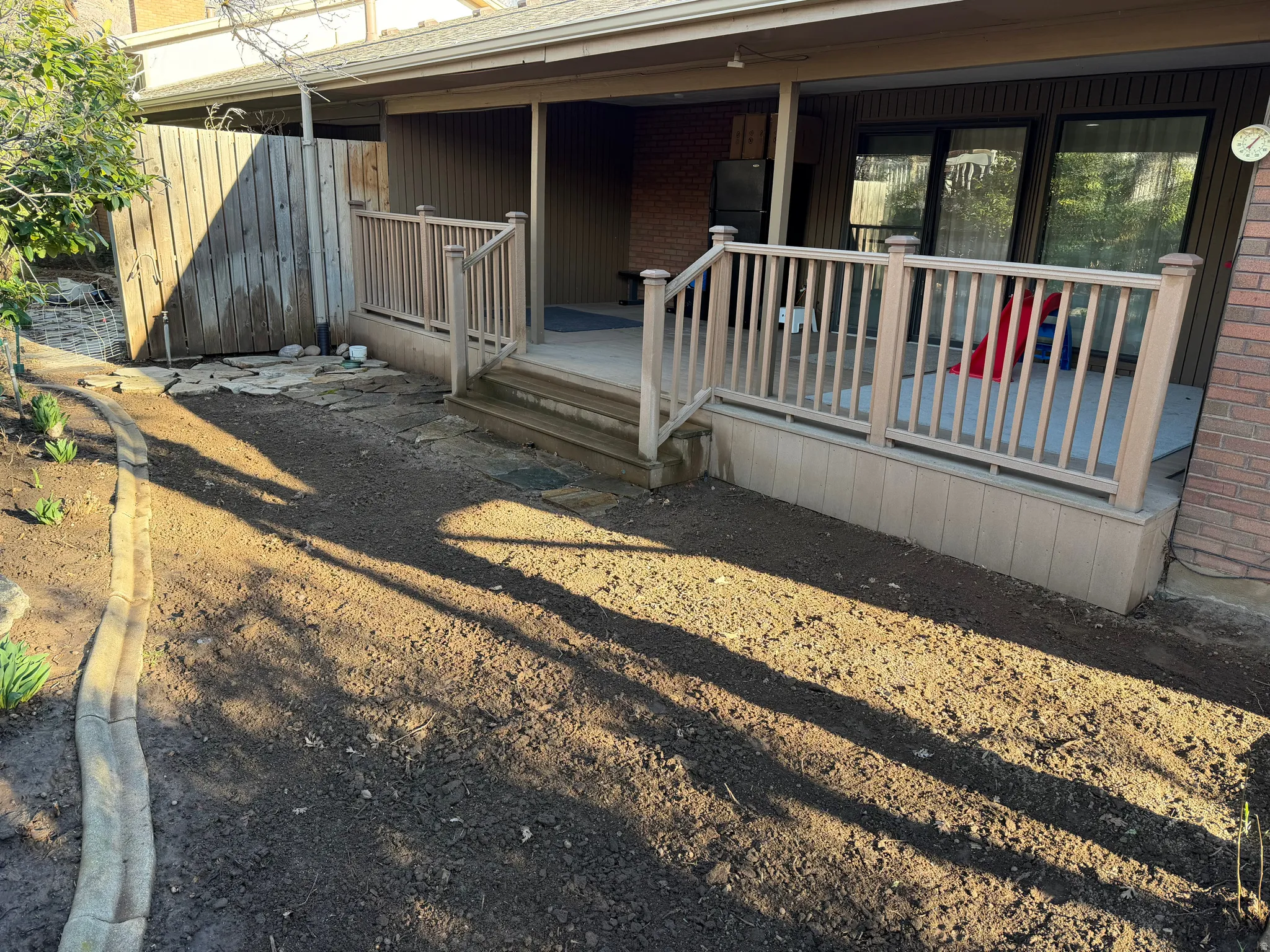 View of exterior entry with brick siding and a wooden deck and newly seeded grass