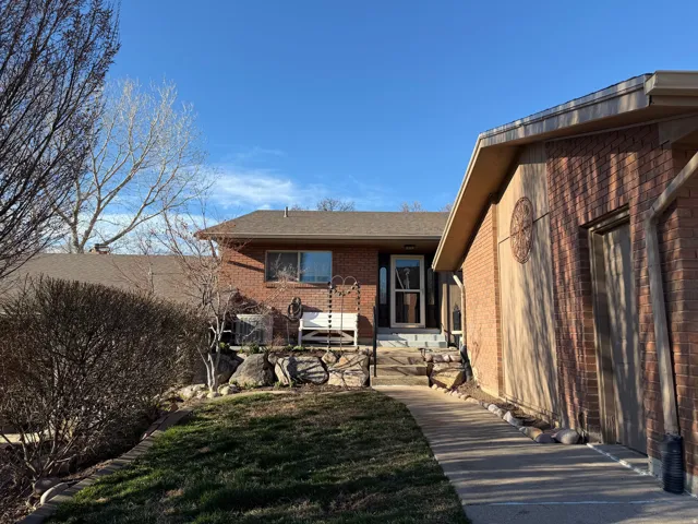 Rear view of house with brick siding, a lawn, and a shingled roof