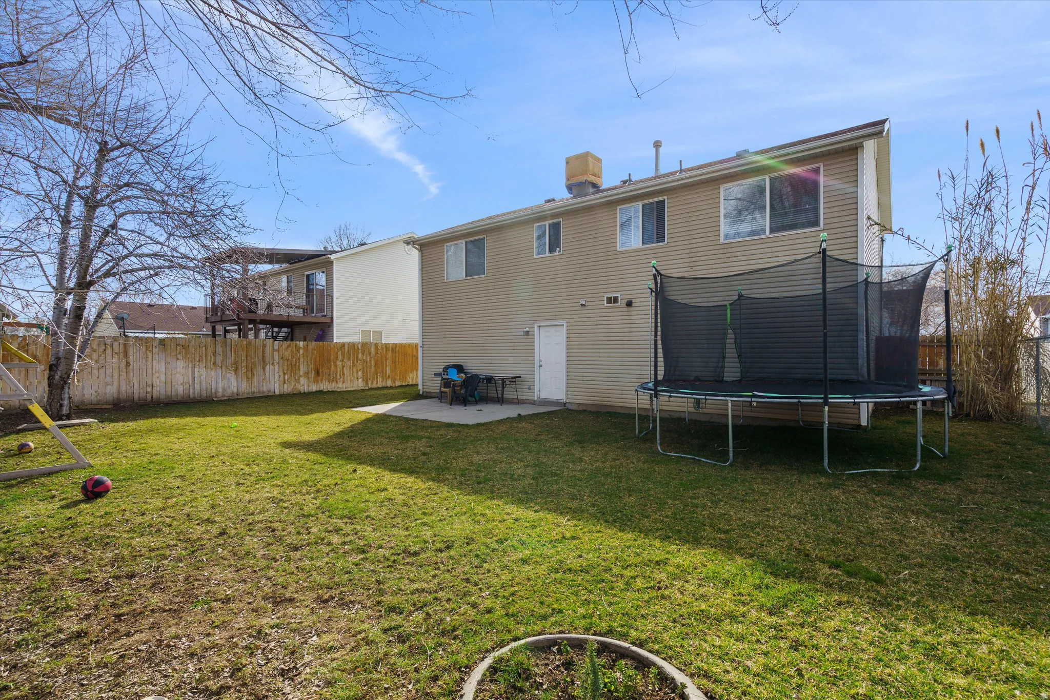 Rear view of property with a patio area, a fenced backyard, and a trampoline