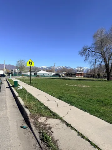 View of street featuring sidewalks, a mountain view, curbs, and traffic signs