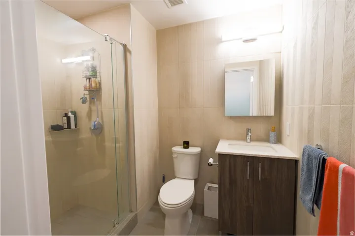 Full bath with vanity, tile walls, light tile patterned floors, and a shower stall