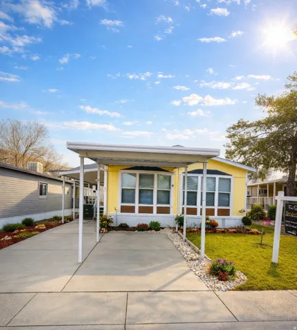 Manufactured / mobile home with a front lawn, a carport, and concrete driveway