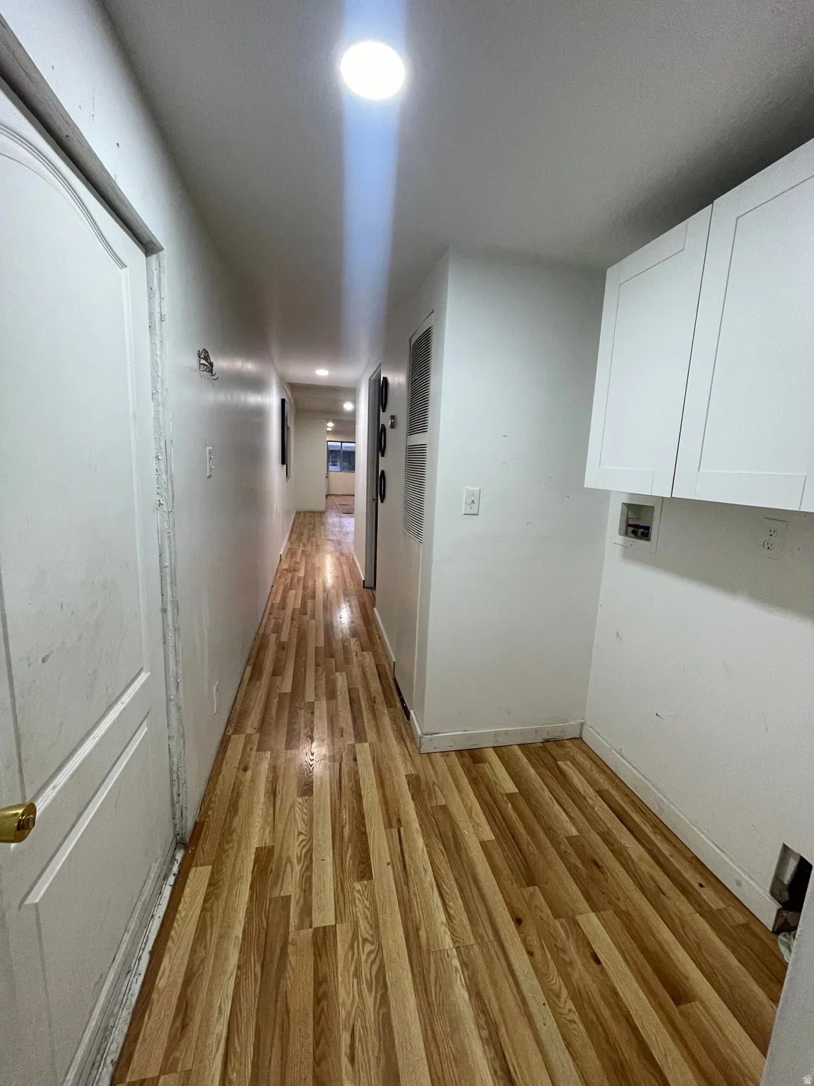 Hallway with light wood-style floors and recessed lighting