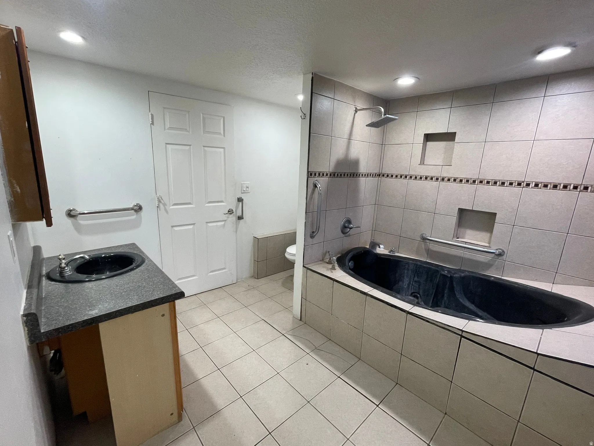 Bathroom with vanity, light tile patterned floors, recessed lighting, tiled shower / bath combo, and a textured ceiling