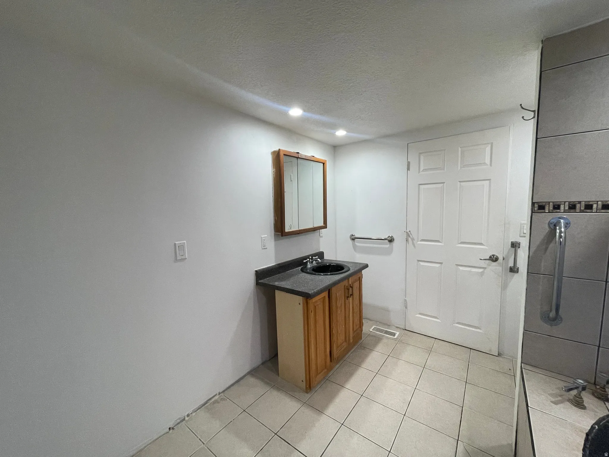Bathroom featuring vanity, a textured ceiling, recessed lighting, and light tile patterned flooring