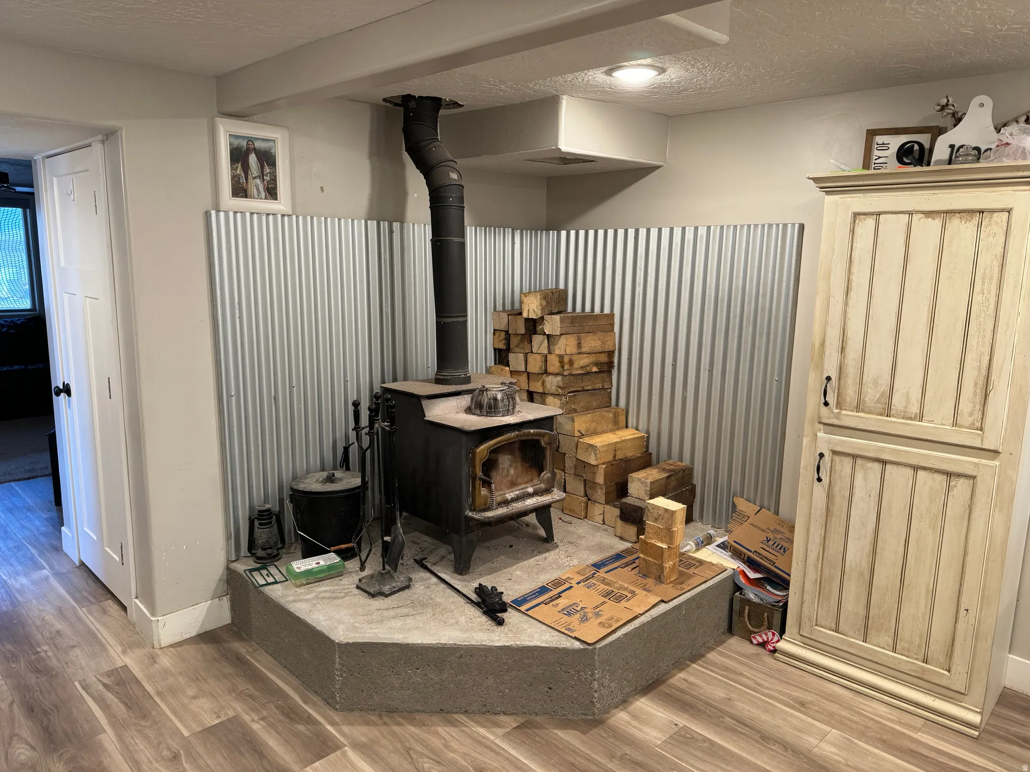 Detailed view of a textured ceiling, a wood stove, and wood finished floors