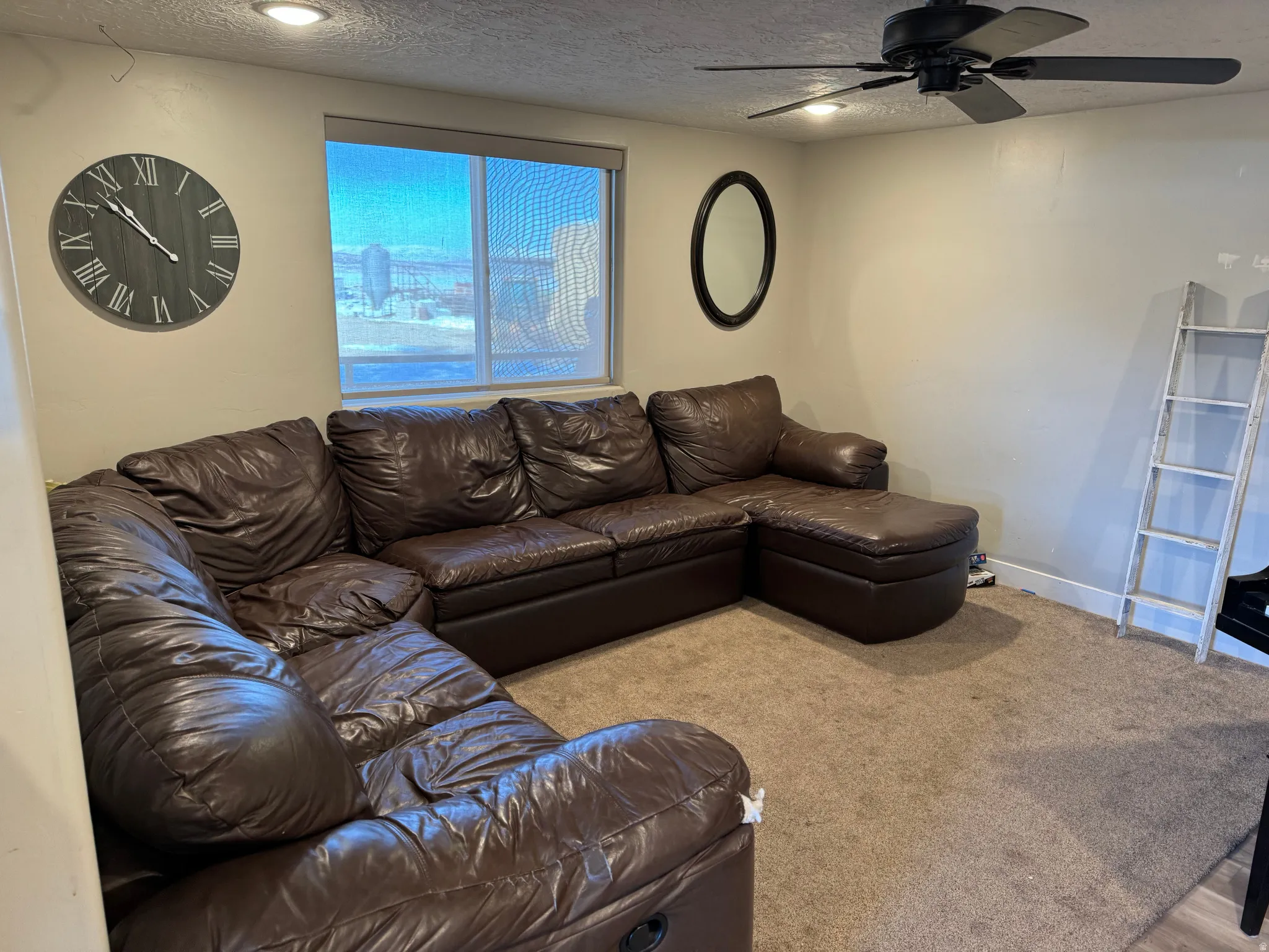 Carpeted living area featuring a textured ceiling and a ceiling fan