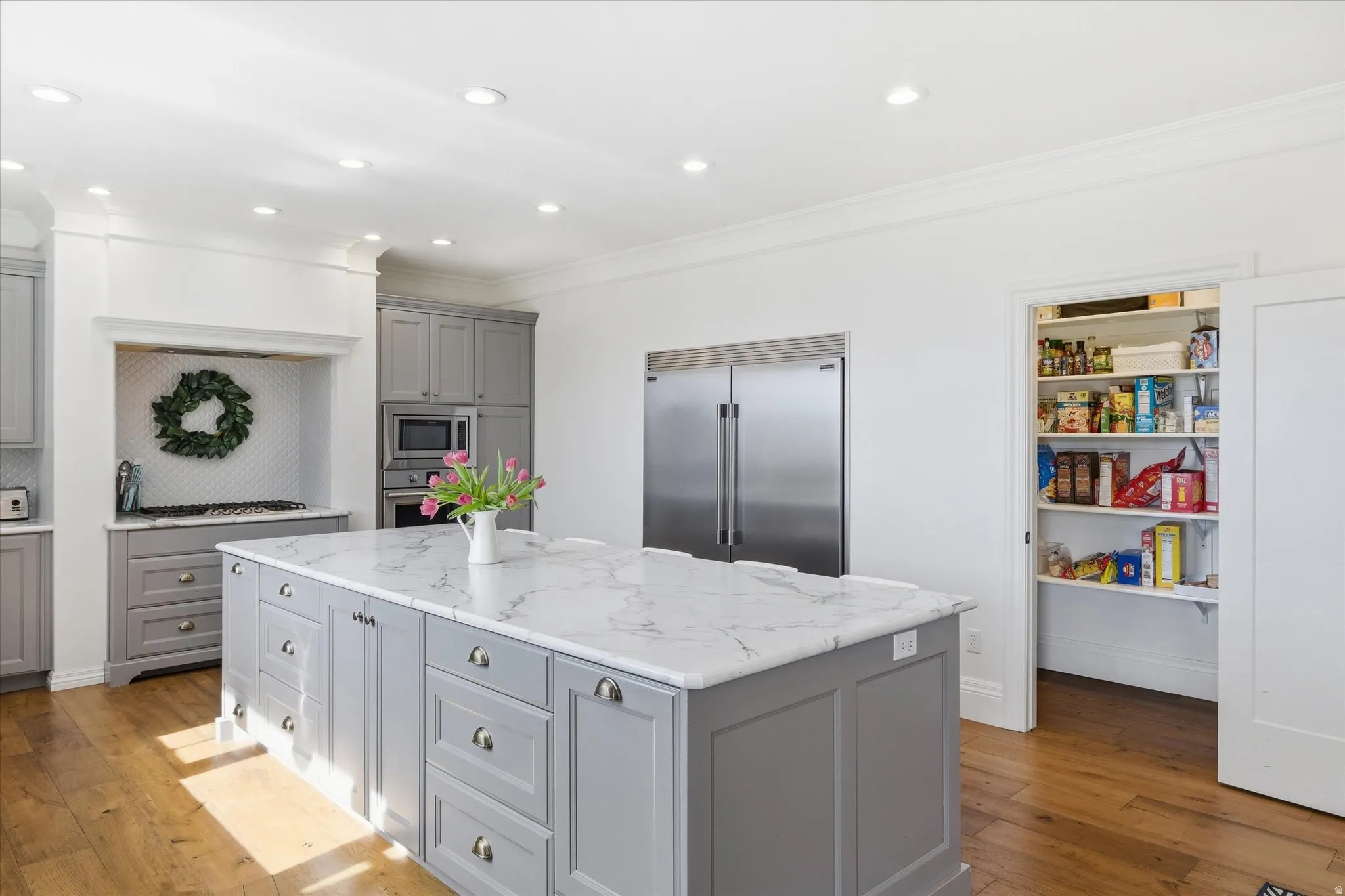 Kitchen with gray cabinets, built in appliances, walk in pantry
