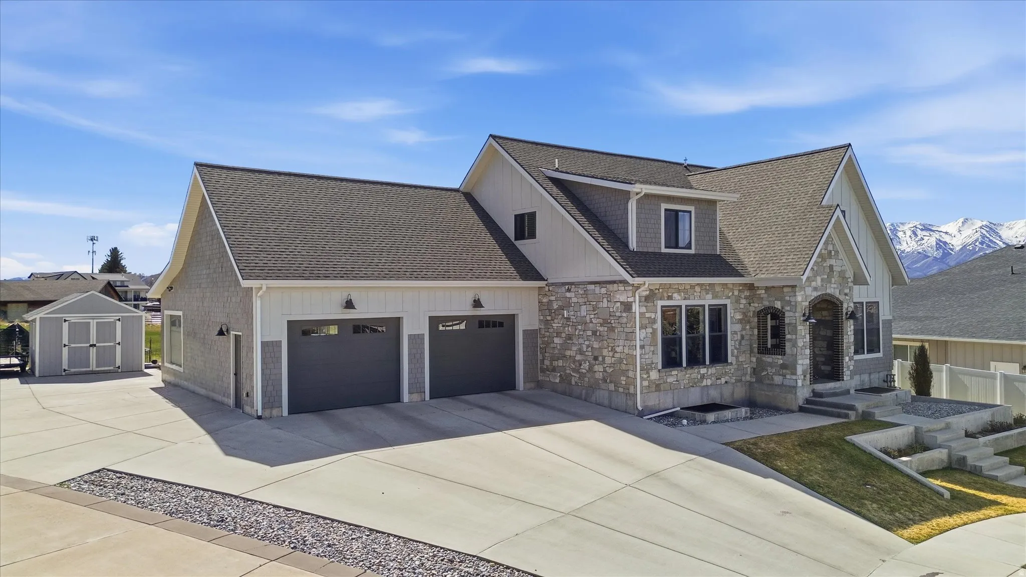 East View of front of home featuring stone siding, concrete driveway, a garage, and roof with shingles