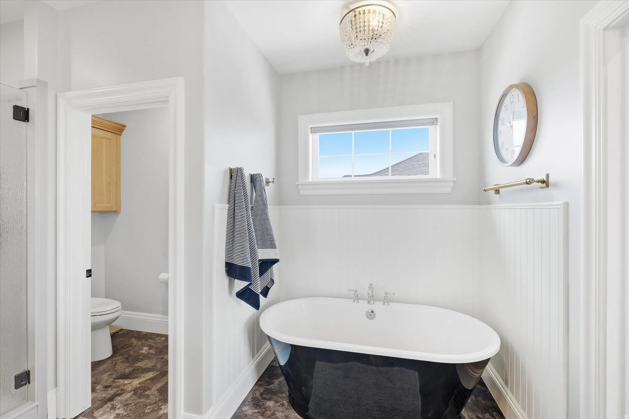 Full bathroom featuring a freestanding tub, a wainscoted wall, and a chandelier