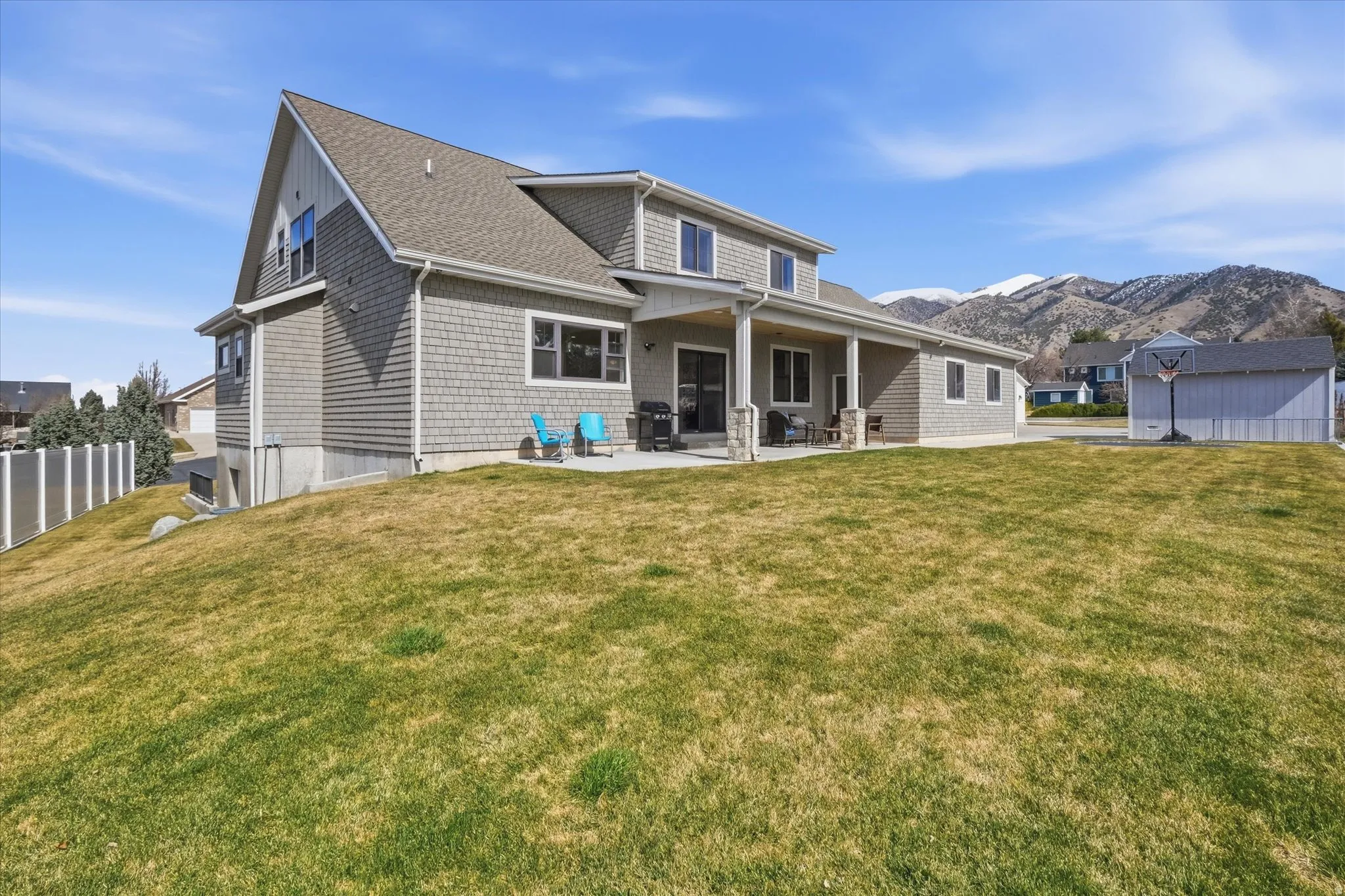 Rear view of property featuring a patio, a shingled roof, and a mountain view