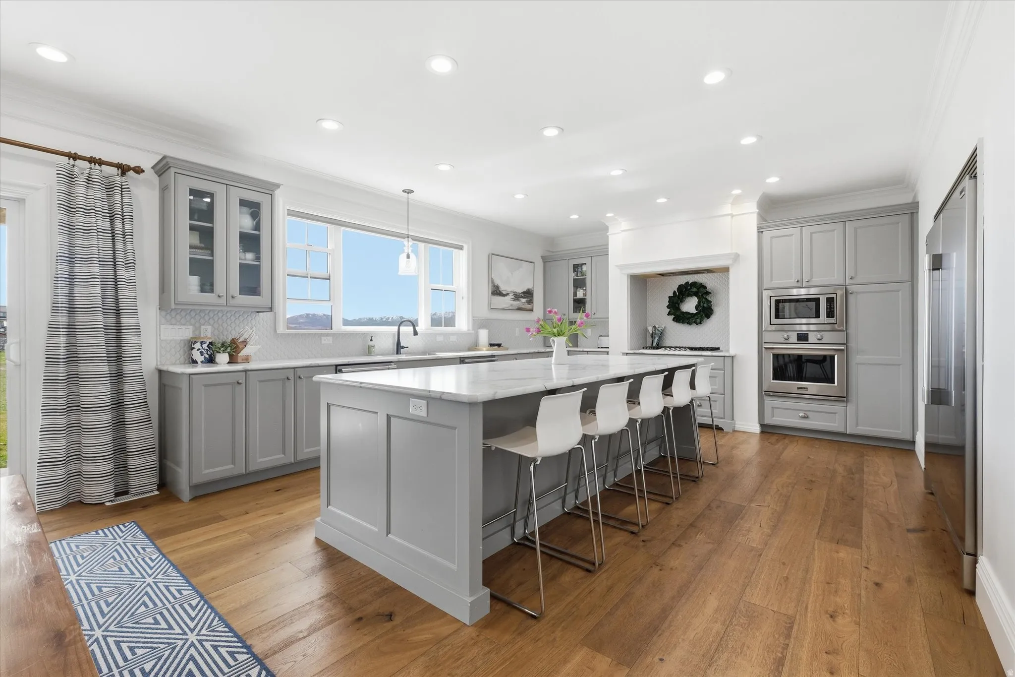 Kitchen featuring gray cabinets, glass insert cabinets, backsplash, and ornamental molding, oversize bar