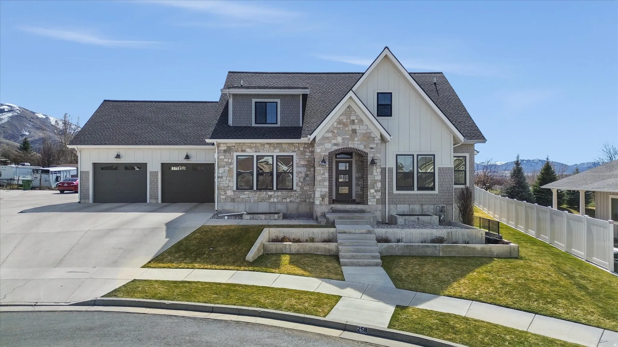 View of front of home featuring a mountain view, stone siding, a shingled roof, and board and batten siding