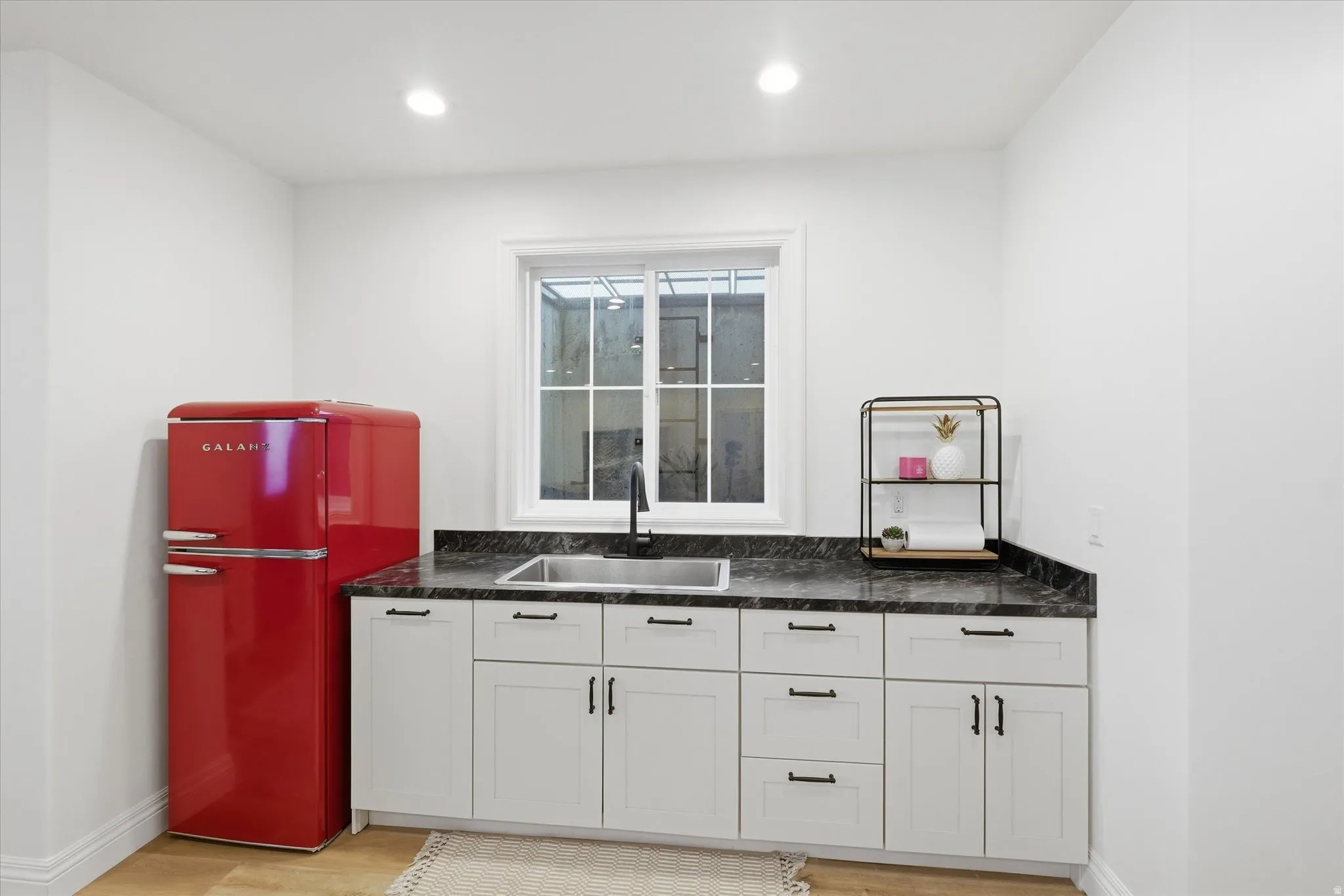 Bar area featuring freestanding refrigerator, white cabinets, light wood-type flooring, and recessed lighting