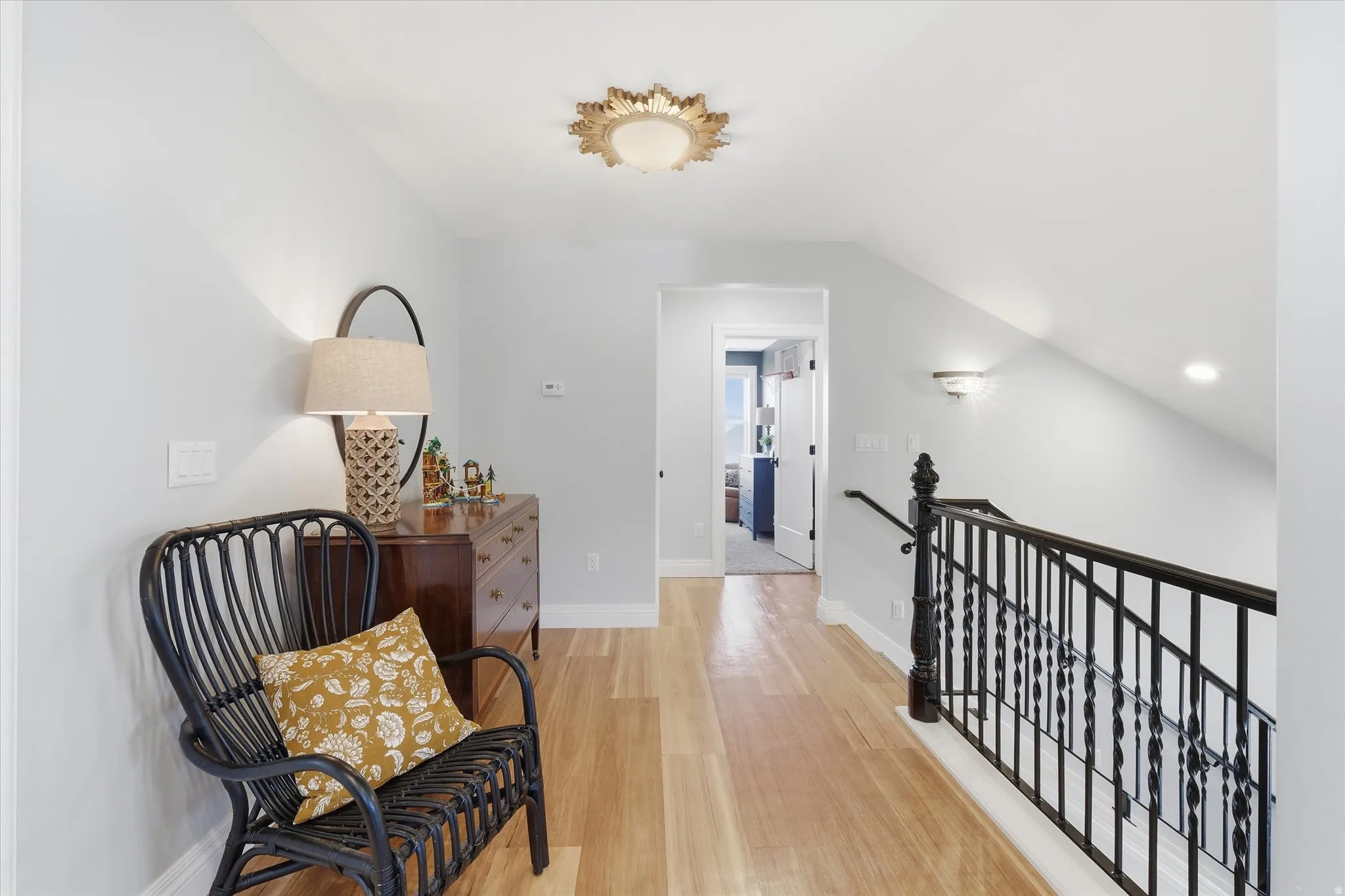Sitting room featuring an upstairs landing, light wood-style flooring, and lofted ceiling