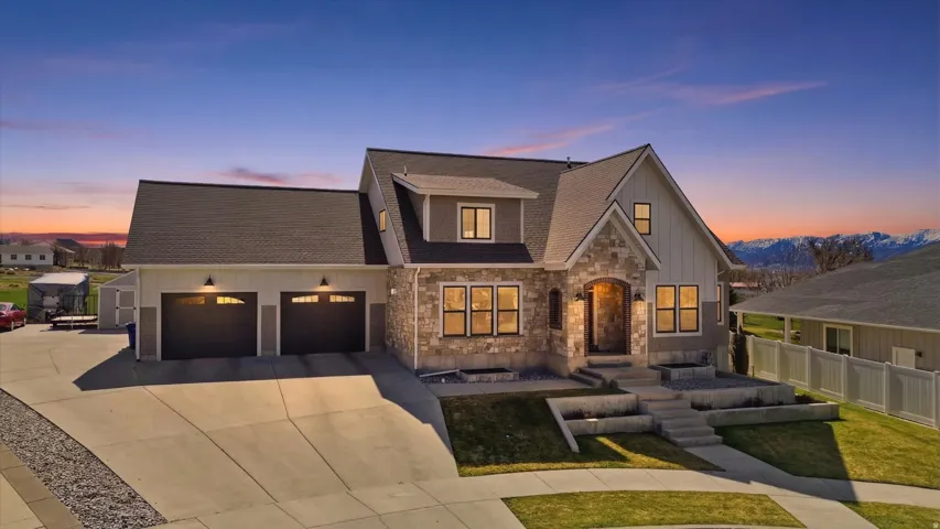 View of front of home with roof with shingles, stone siding, concrete driveway, an attached garage, and board and batten siding