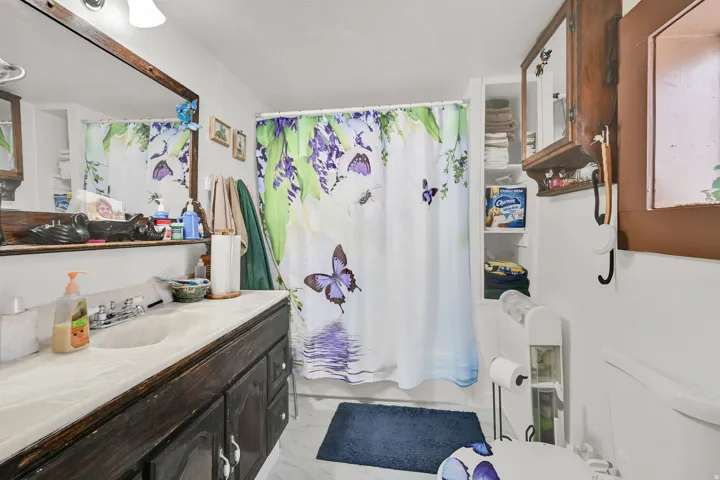 Full bathroom featuring vanity, shower / bath combination with curtain, and light marble finish flooring