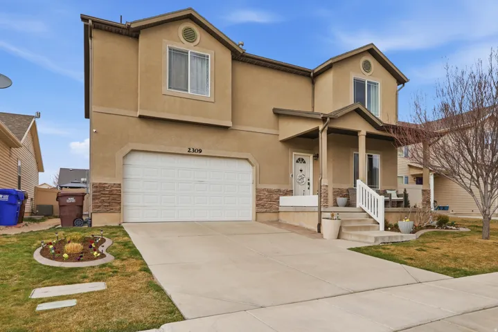 View of front of house with stone siding, an attached garage, stucco siding, and covered porch