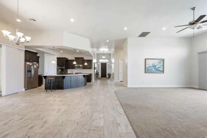 Kitchen featuring open floor plan, a spacious island, a breakfast bar, stainless steel appliances, and suspended lighting