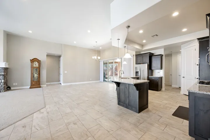 Kitchen with light stone countertops, an island with sink, a breakfast bar area, and open floor plan