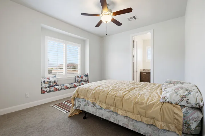 Bedroom featuring carpet, ceiling fan, and ensuite bath
