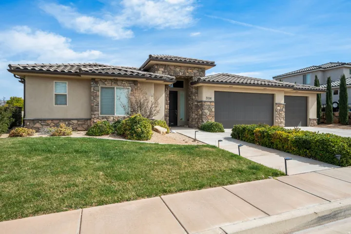 Prairie-style house with stone siding, a garage, a front yard, driveway, and stucco siding