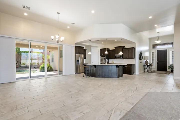 Kitchen with a breakfast bar, open floor plan, dark wood finish cabinetry, stainless steel appliances, and a high ceiling